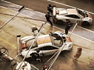 Dos McLaren MP4 GT3 librea Gulf en movimiento en pit lane durante repostaje – fotografía artística edición 14 ejemplares