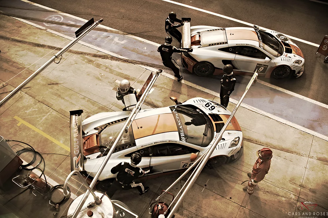 Dos McLaren MP4 GT3 librea Gulf en movimiento en pit lane durante repostaje – fotografía artística edición 14 ejemplares