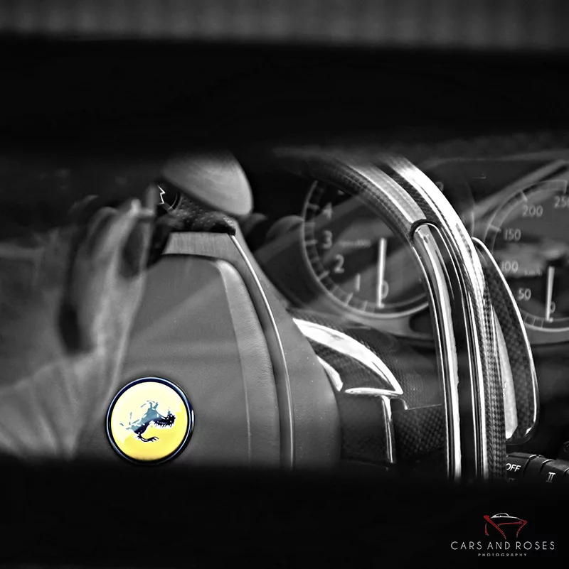 Volante Ferrari en blanco y negro con logo del Cavallino Rampante, ejemplo de fotografía macro de detalle de coches