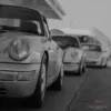 Fotografía en blanco y negro de una fila de Porsche 911 clásicos antiguos alineados, composición artística monocroma de varios 911 vintage, arte de pared automovilístico de colección edición limitada