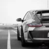 Pintura decorativa del coche Fotografía Porsche 997 GT3 3.8 en blanco y negro con técnica de color selectivo, único punto de color en los faros traseros rojos bajo cielo nublado, fotografía artística moody edición limitada