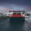 Fotografía Porsche GT3 RS y amanecer Porsche 911 GT3 RS 992 rojo visto desde atrás en pista de carreras al amanecer con cielo rojizo y anaranjado, alerón trasero prominente y frenos cerámicos visibles