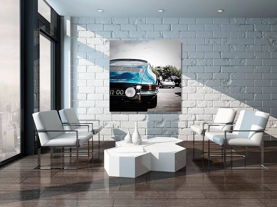 Imagen 2: Salón moderno con pared de ladrillo blanco, cuadro grande de Porsche 911 Type 901 azul colgado en el centro, sillones blancos, mesa baja geométrica blanca y lámpara de araña, decoración interior contemporánea