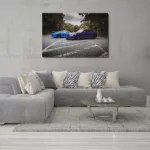 Salón moderno con cuadro grande de Porsche 991 GT3 y GT3 RS colgado en la pared, sofá gris con cojines claros y de cebra, café circular y alfombra suave, decoración contemporánea. mesa de