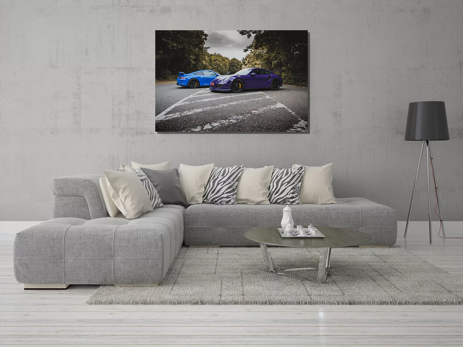 Salón moderno con cuadro grande de Porsche 991 GT3 y GT3 RS colgado en la pared, sofá gris con cojines claros y de cebra, café circular y alfombra suave, decoración contemporánea. mesa de