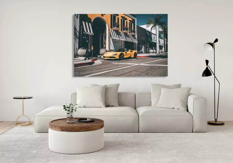 Salón moderno con cuadro grande de Ferrari F488 Spider amarilla colgado en la pared, sofá claro con cojines, mesa de café redonda y lámpara de pie, decoración contemporánea.
