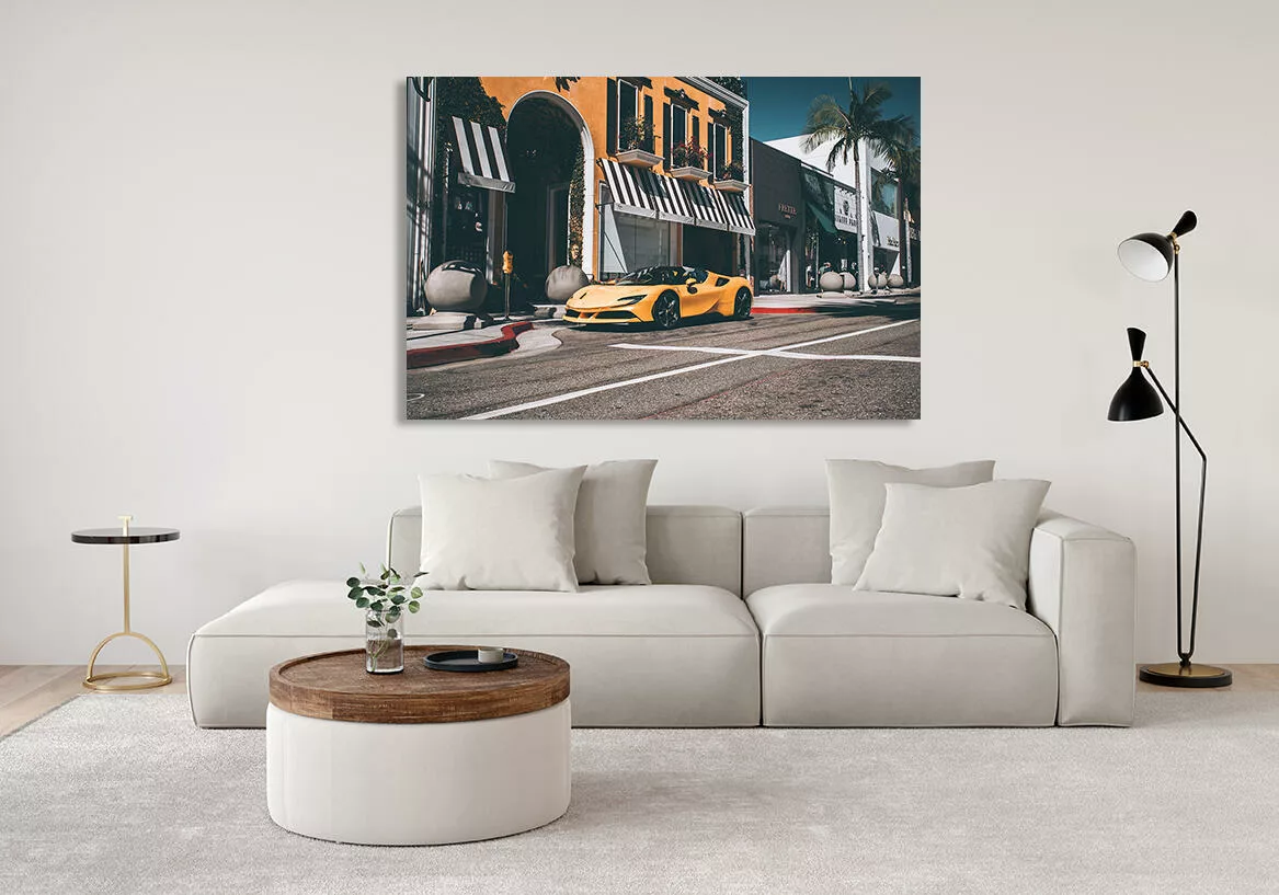 Salón moderno con cuadro grande de Ferrari F488 Spider amarilla colgado en la pared, sofá claro con cojines, mesa de café redonda y lámpara de pie, decoración contemporánea.