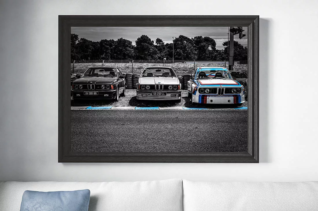 Fotografía enmarcada de BMW clásicos de carreras en blanco y negro exhibida en interior moderno sobre pared clara con decoración minimalista