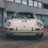 Porsche 911 Clásico blanco de competición en pits del circuito Dijon-Prenois, fotografía artística en blanco y negro con acabado moody vintage, jaula antivuelco y detalles racing visibles