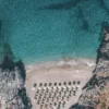 Fotografía aérea cala secreta Platanias Creta – aguas turquesas cristalinas y sombrillas de playa vistas desde dron