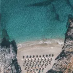Fotografía aérea cala secreta Platanias Creta – aguas turquesas cristalinas y sombrillas de playa vistas desde dron