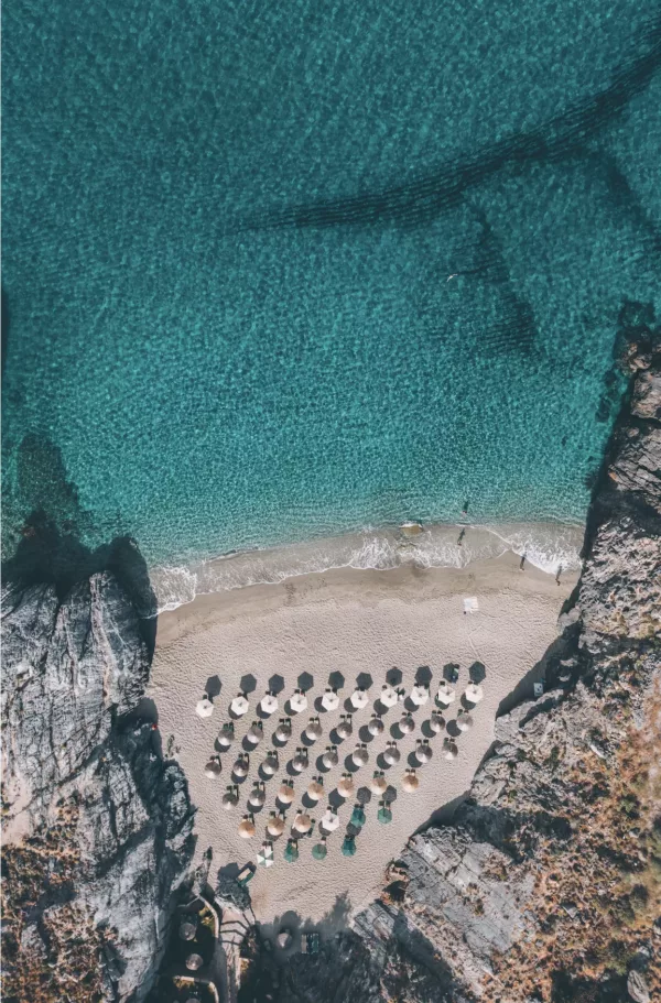 Fotografía aérea cala secreta Platanias Creta – aguas turquesas cristalinas y sombrillas de playa vistas desde dron