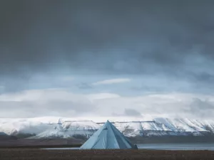 Fotografía del Svalbard con tienda solitaria frente a los fiordos árticos nevados bajo un cielo dramático