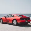 Ferrari 348 TS rojo aparcado frente al océano en la 17-Mile Drive de Pebble Beach, California, vista trasera tres cuartos