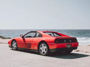 Ferrari 348 TS rojo aparcado frente al océano en la 17-Mile Drive de Pebble Beach, California, vista trasera tres cuartos