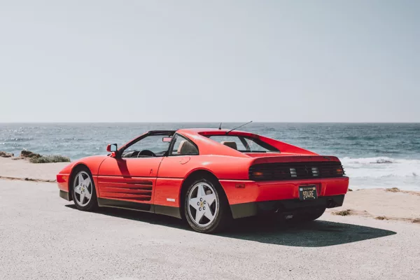 Ferrari 348 TS rojo aparcado frente al océano en la 17-Mile Drive de Pebble Beach, California, vista trasera tres cuartos