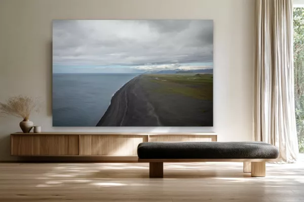 Cuadro fotografía de la playa de arena negra de Islandia sobre un aparador de roble claro en un salón escandinavo