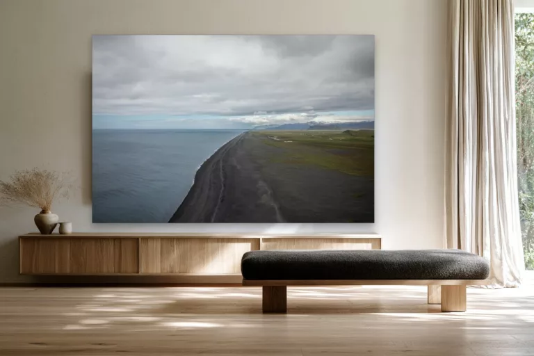 Cuadro fotografía de la playa de arena negra de Islandia sobre un aparador de roble claro en un salón escandinavo