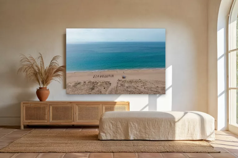 Cuadro fotografía de la playa de Zahara de los Atunes sobre un aparador de rattán en un luminoso salón andaluz
