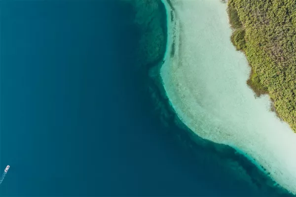 Fotografía aérea del lago Kournas en Creta: agua azul profundo, aguas turquesa poco profundas y una pequeña barca